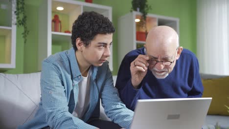 Curious-grandfather-looking-at-what-his-cute-grandson-is-doing-while-looking-at-laptop.